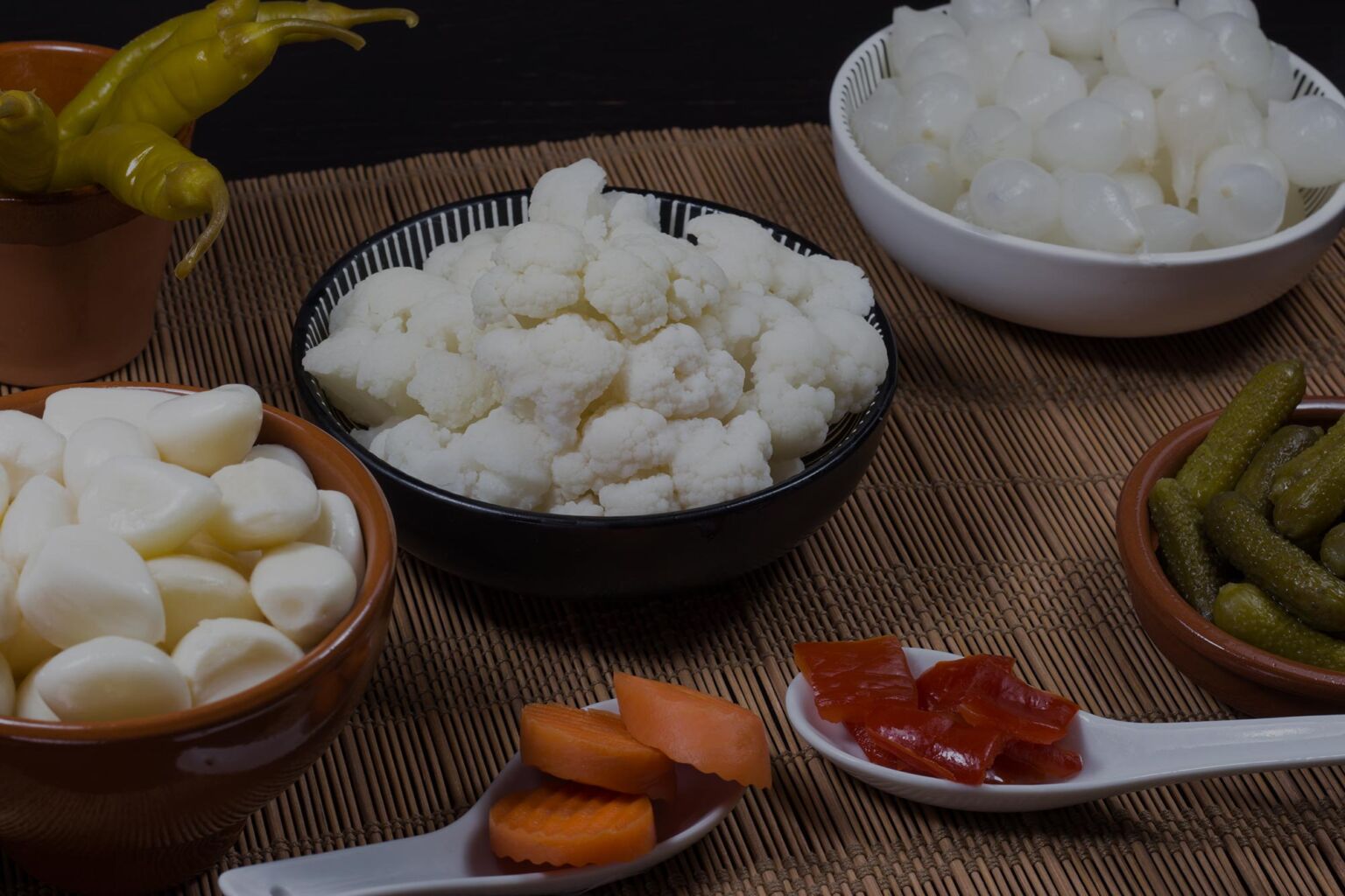 recipientes con varios encurtidos como ajos, pimiento, cebolletas o coliflor
